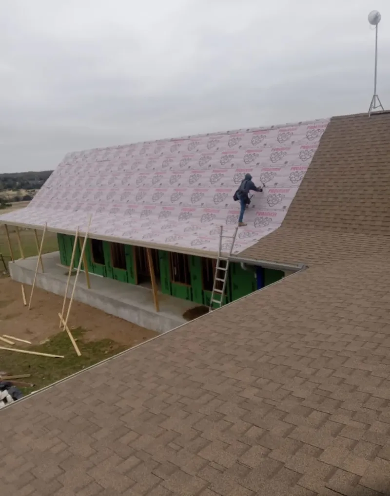 Worker preparing underlayment for a metal roof installation in Prospect